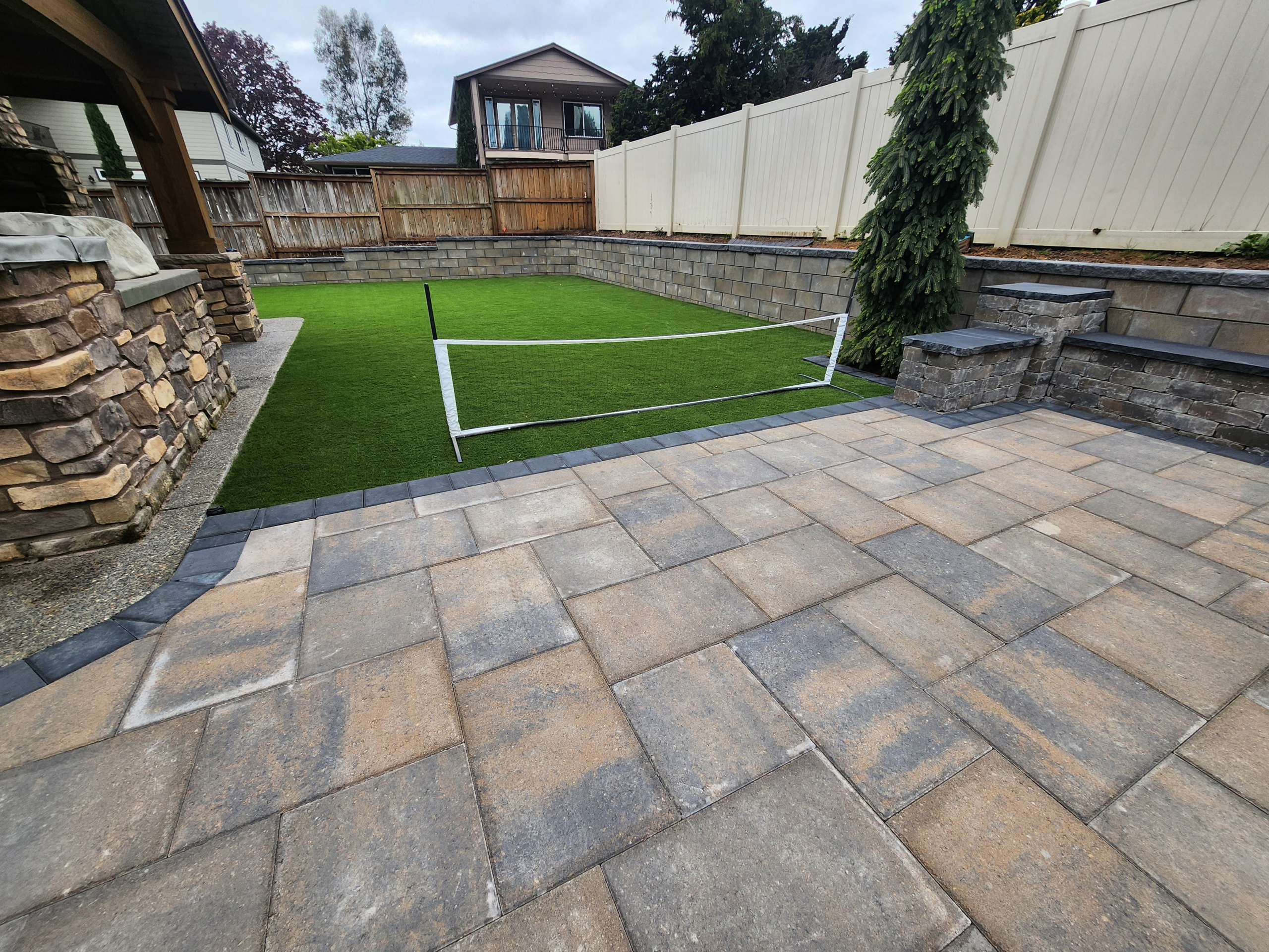 Paver patio with lawn, steps, and retaining walls