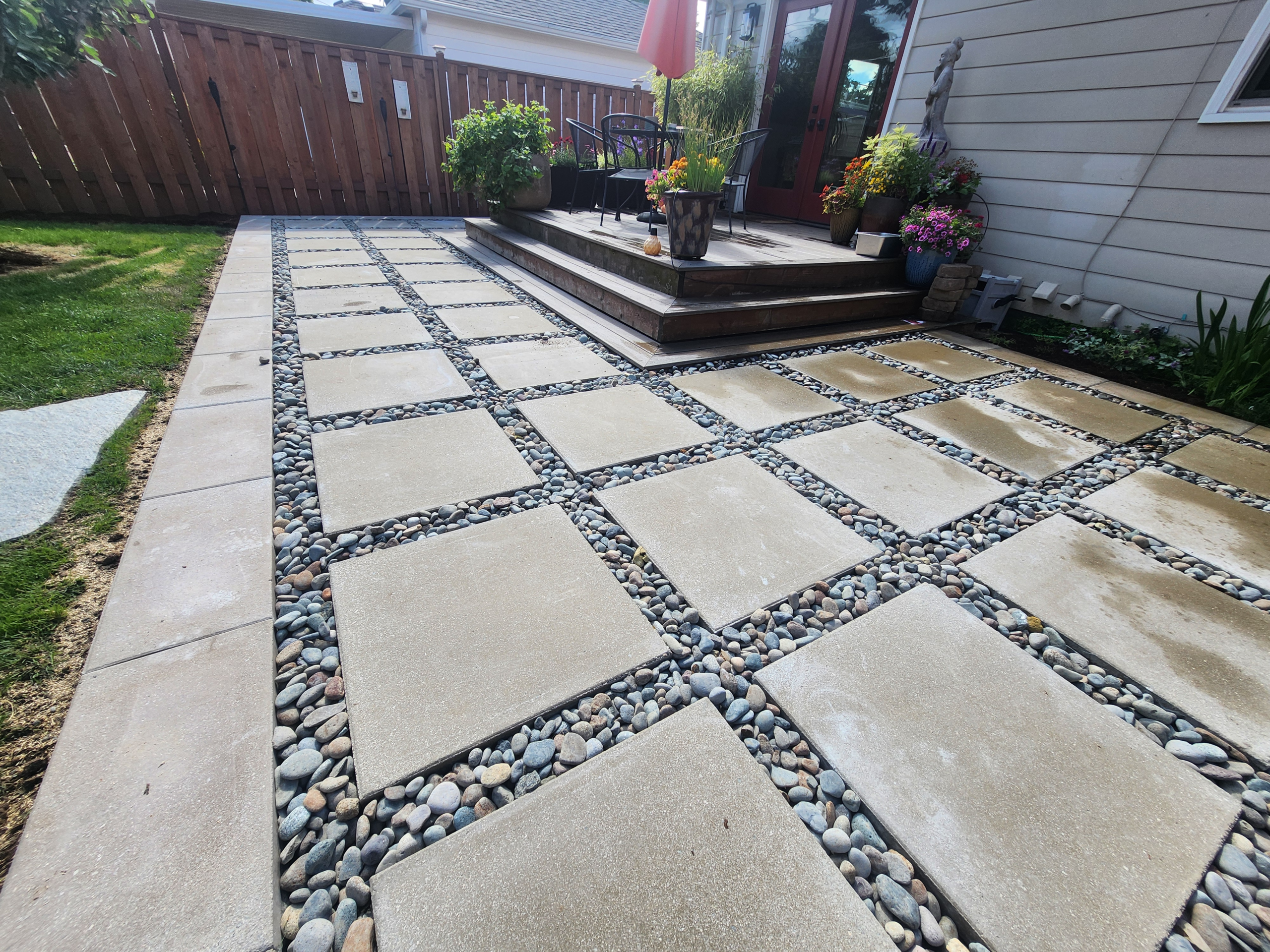 Large patio slabs separated by decorative river-rock bands