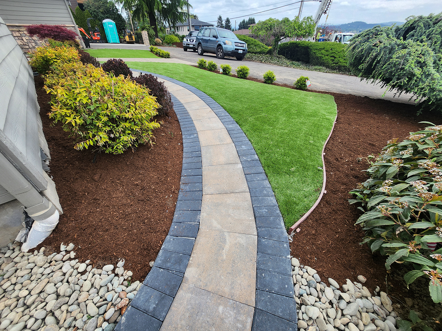 Curved paver walkway beside lawn and mulched planting beds