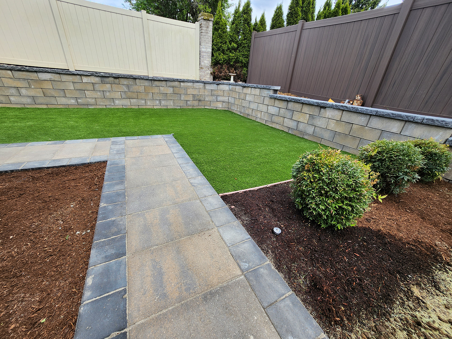 walkway-retaining-wall-1.webp Walkway beside a landscaped retaining wall